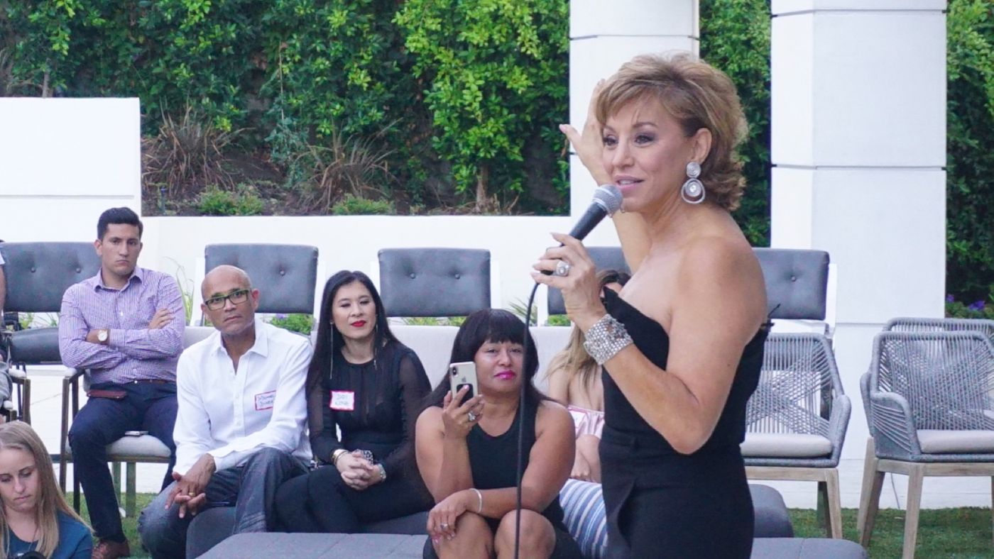 Forbes Riley speaking to an audience with a microphone